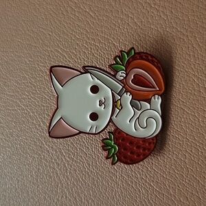 Cat holding knife with strawberries enamel pin